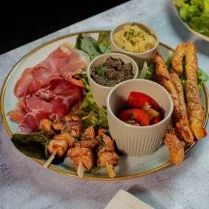 Assiette méditerranéenne servie à L’AGRICOLE Nevers avec houmous maison, tapenade, charcuterie et brochettes de poulet mariné