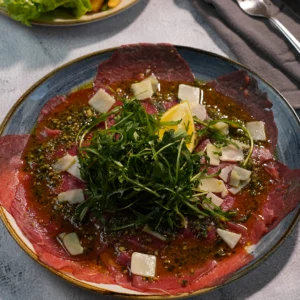 Carpaccio de bœuf servi à L’AGRICOLE Nevers avec pesto maison, parmesan, roquette et citron