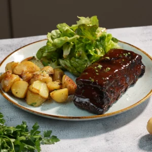 Travers de porc marinés servis à L’AGRICOLE Nevers avec sauce barbecue maison, pommes grenailles et salade